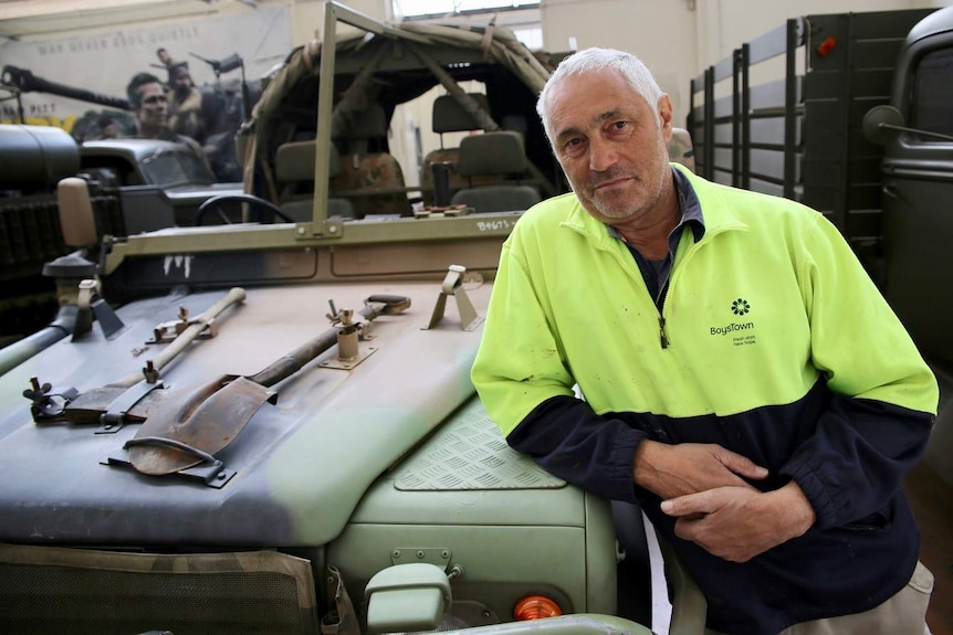 Phillip Cacciola stands in front of an army jeep.