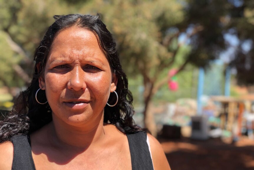 A head shot of Indigenous woman Leetisha Jones standing in front of a background of trees in soft focus.