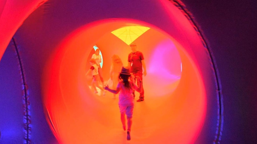 A child runs through the coloured tunnels of a blow up sculpture.