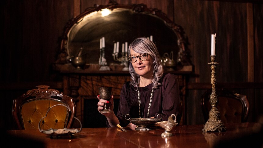 Colour photo of creative producer Kirsten Siddle sitting in a 19th century styled dining room set in A Midnight Visit.
