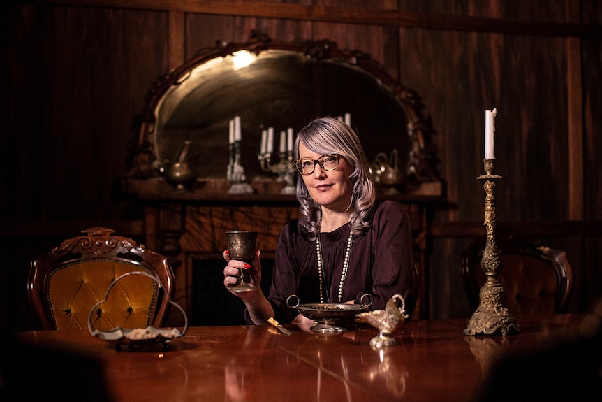 Colour photo of creative producer Kirsten Siddle sitting in a 19th century styled dining room set in A Midnight Visit.