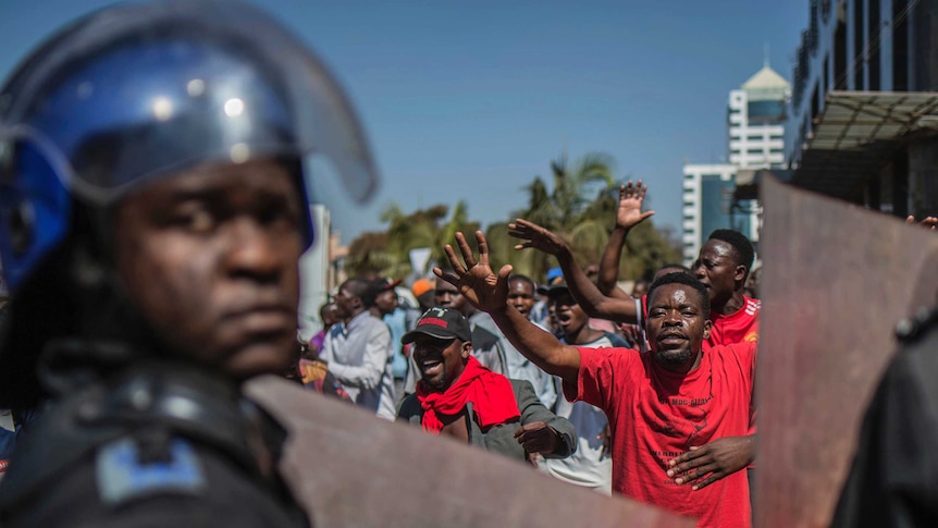 Police patrol outside the Zimbabwe Electoral Commission offices as opposition supporters gather