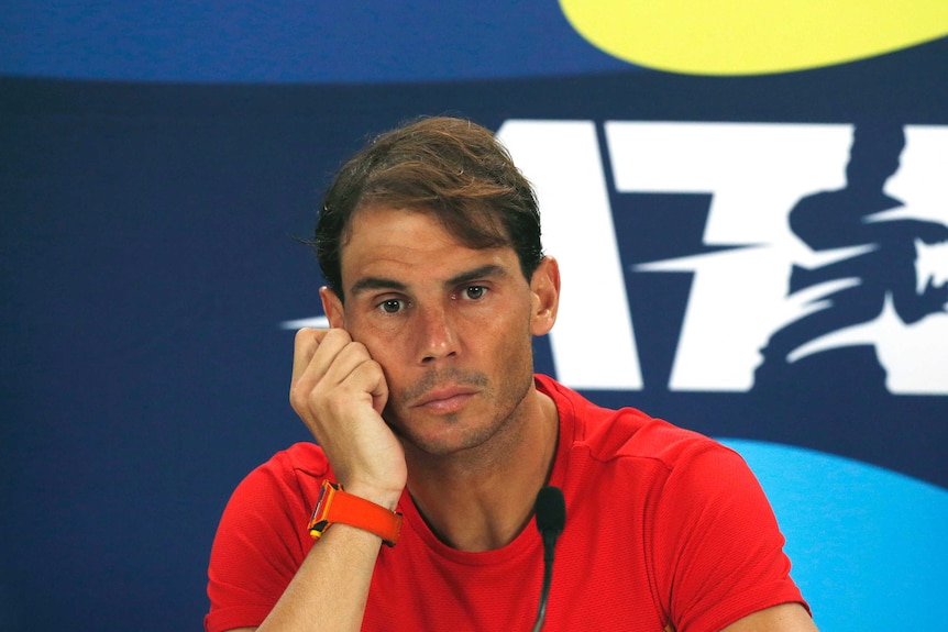 Rafael Nadal holds his clenched fist next to his head with a sad look on his face