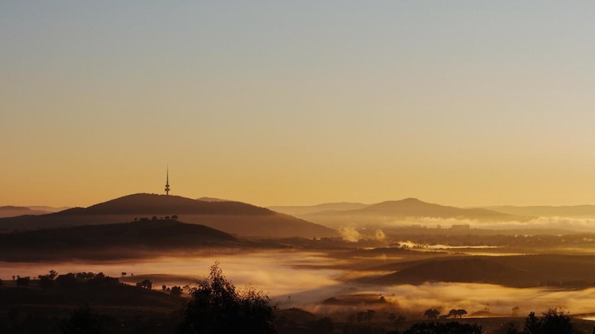 A foggy sunrise in Canberra with Black Mountain Tower on the hill.