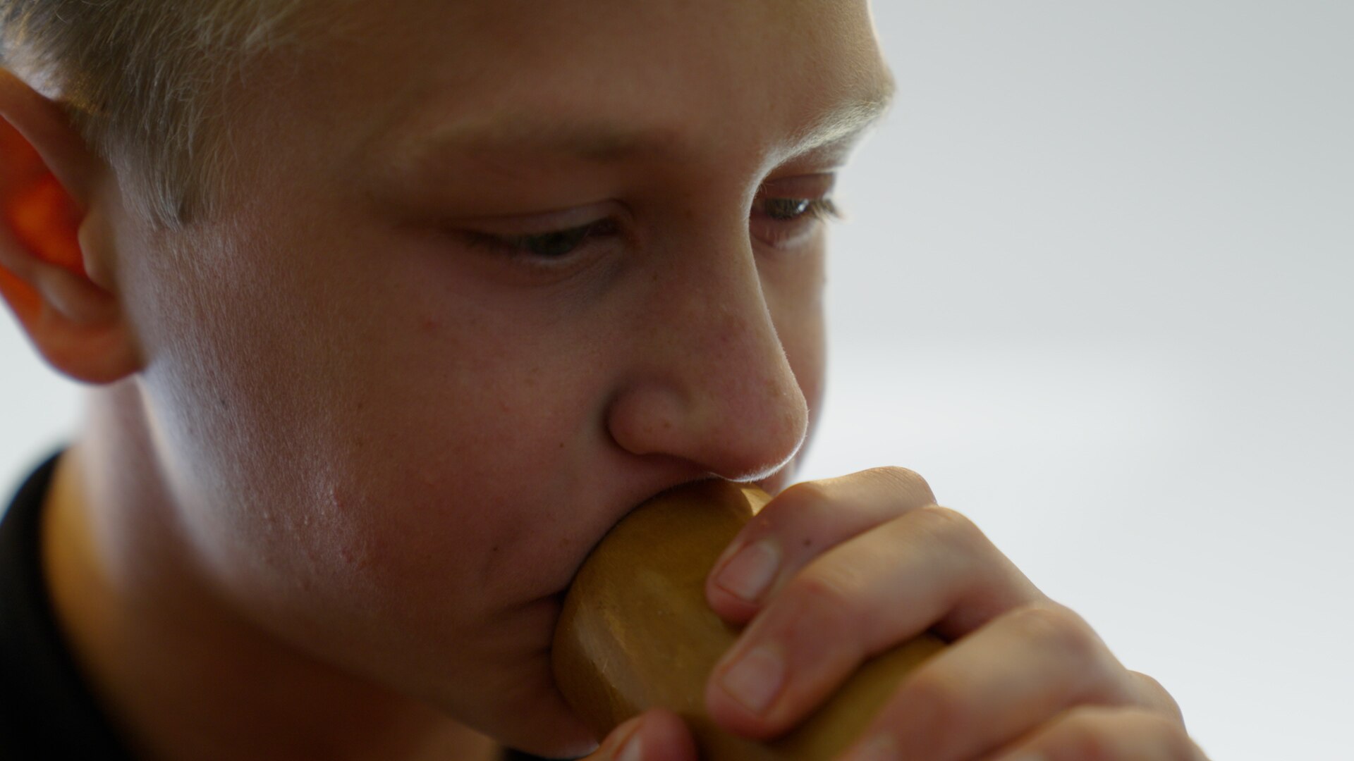 A close up photo of Malakai blowing on the yidaki