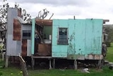 A blue house with its roof torn off.