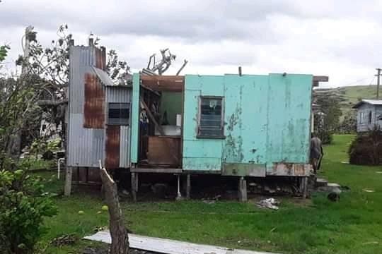 A blue house with its roof torn off.