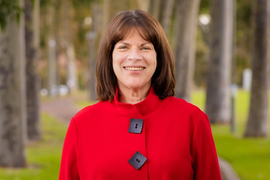 A mid-shot of Curtin University vice-chancellor Harlene Hayne smiling for a photo wearing a red coat outdoors.