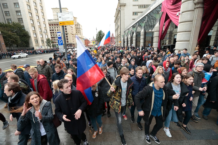 Demonstrators shout slogans and carry the Russian flag. The protesters are mostly young people.