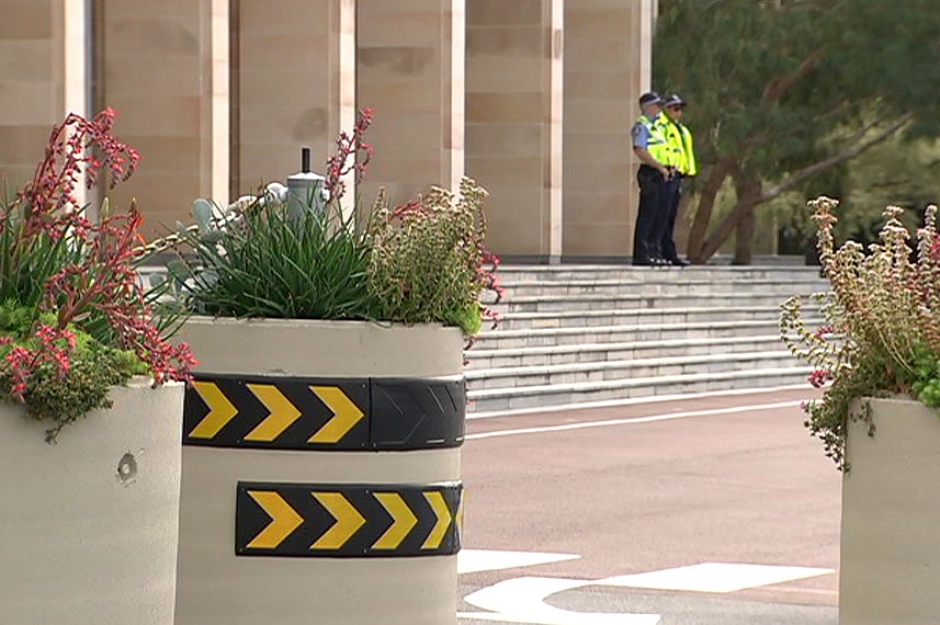 Security bollards out the front of WA's Parliament House with two police guards in the background.