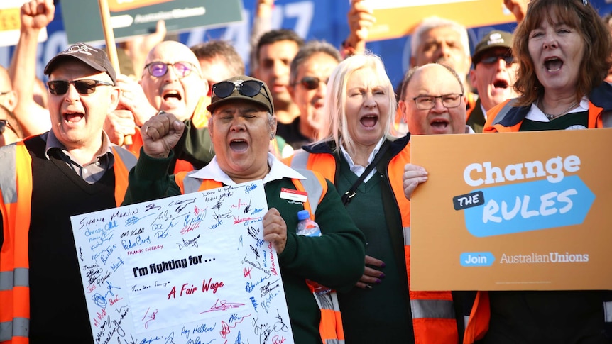 Striking bus drivers hold placards, many with fists raised, as they chant slogans