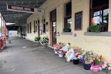 A white brick building with flowers on the ground and a sign that reads National Hotel