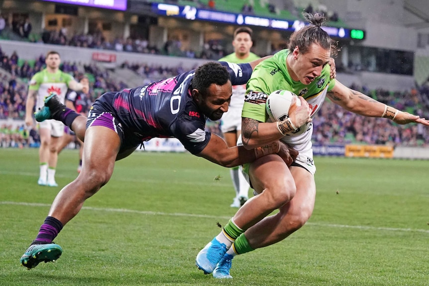 Charnze Nicoll-Klokstad tries to shrug the tackle of Justin Olam, who has one hand on his shoulder and one around his waist