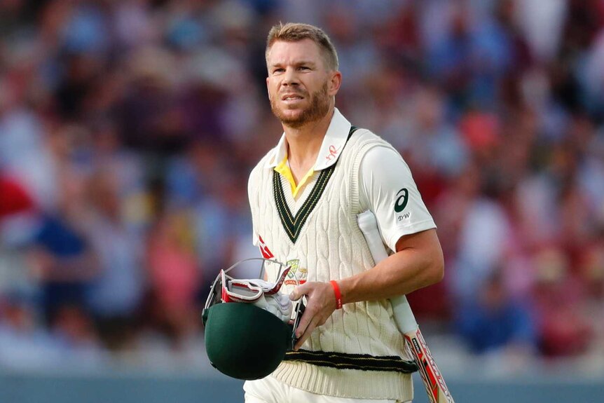 Warner walking off with helmet in hand and bat under his arm.