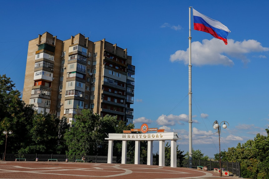 A Russian flag flies in a sunny, empty city square.