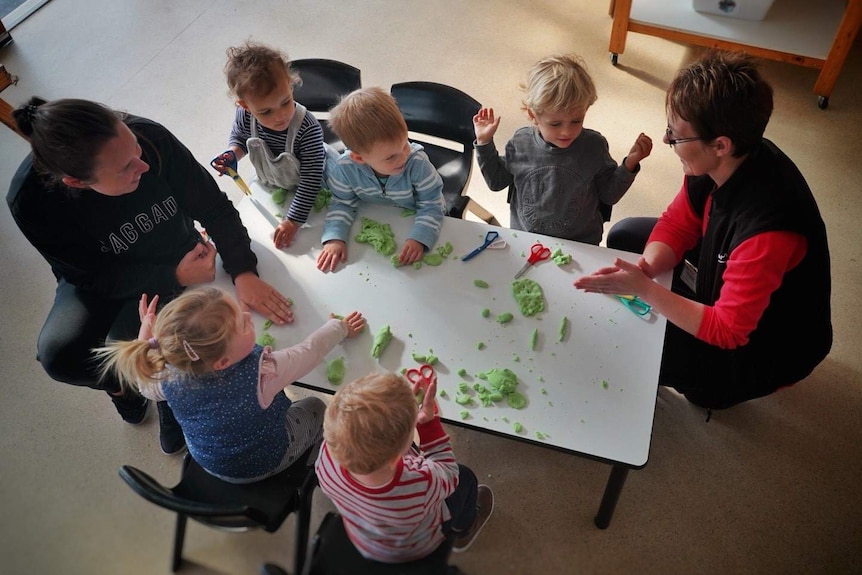 Children and educators sit at a table.