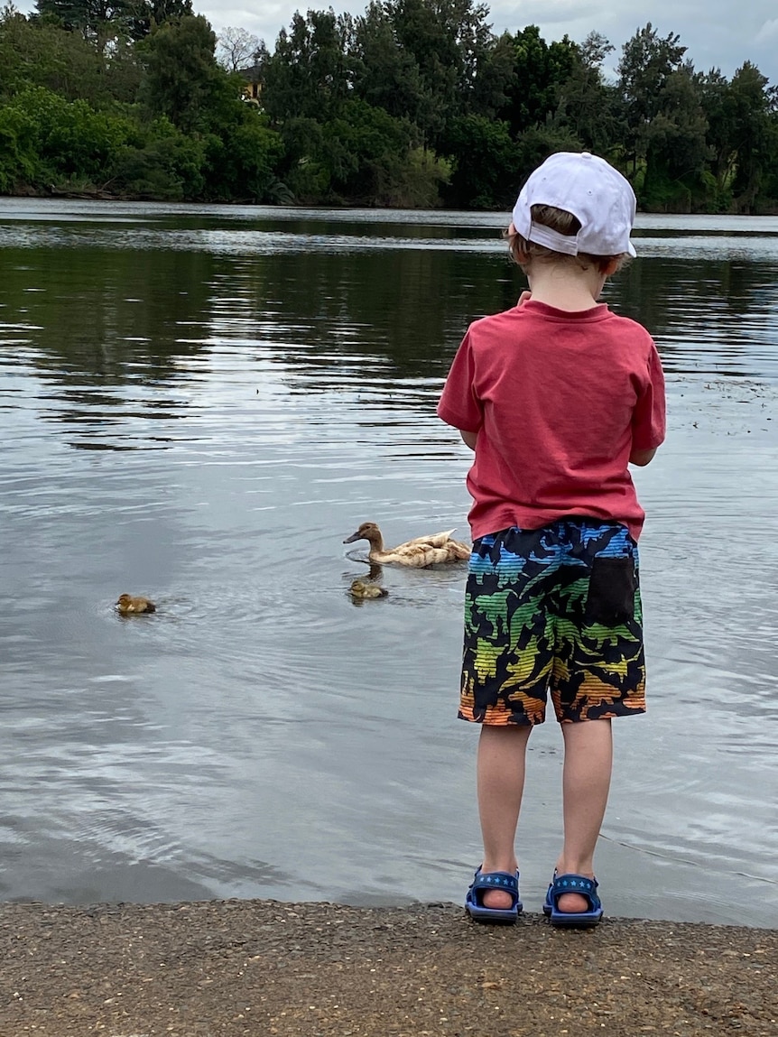 A boy stands beside a lake for a story on telling your child about their autism diagnosis.