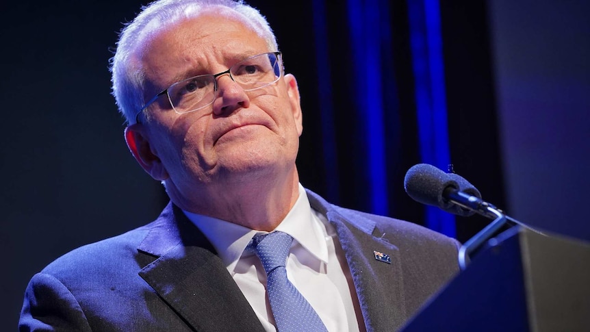 Scott Morrison listens to a question standing in front of a podium at a press conference.