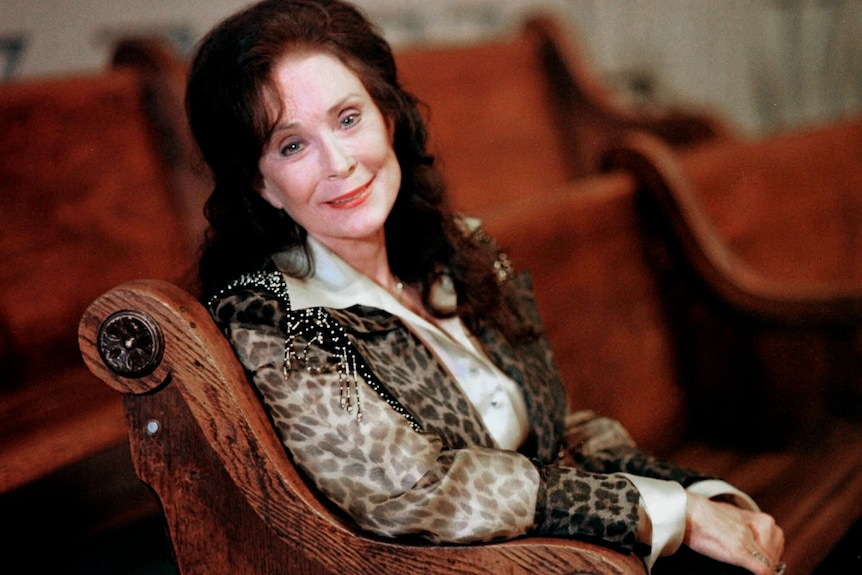 lynn in a red velvet lined chair, wearing leopard print and tassles, and her long brown hair half up