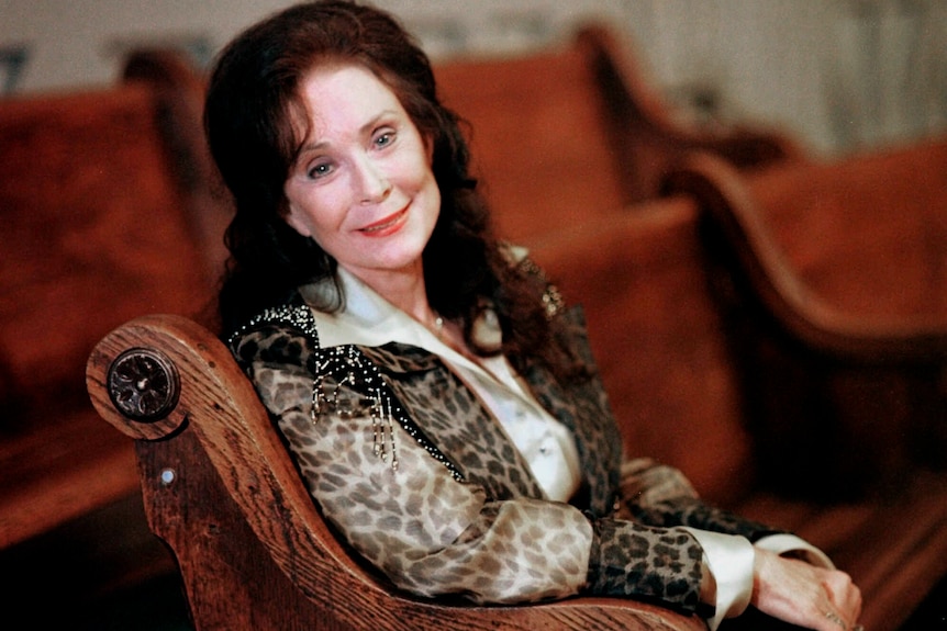 lynn in a red velvet lined chair, wearing leopard print and tassles, and her long brown hair half up