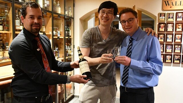 A hotel sommelier, author Zhang Wei and hotel manager Sandro Bernasconi pose with the scotch.