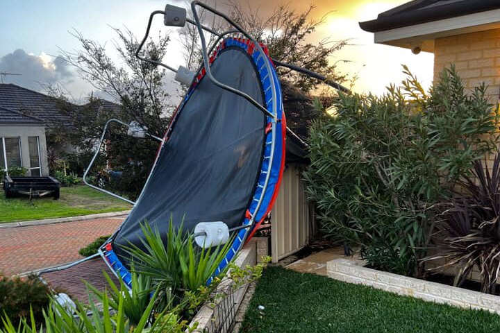 A trampoline lies on its side in a garden after being blown away in severe weather.
