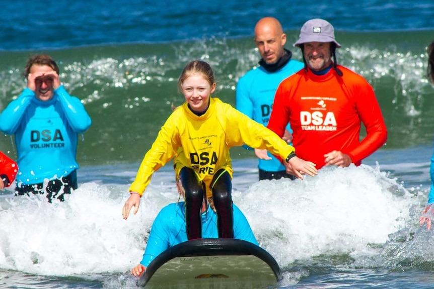 Ettie surfing with the help of the Disabled Surfers Association of Australia