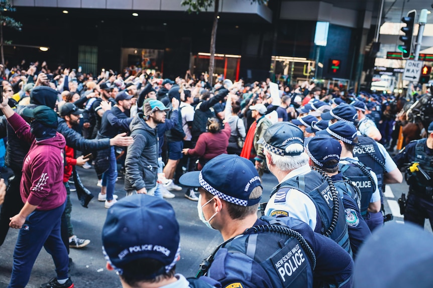 Angry people stand in front of police.