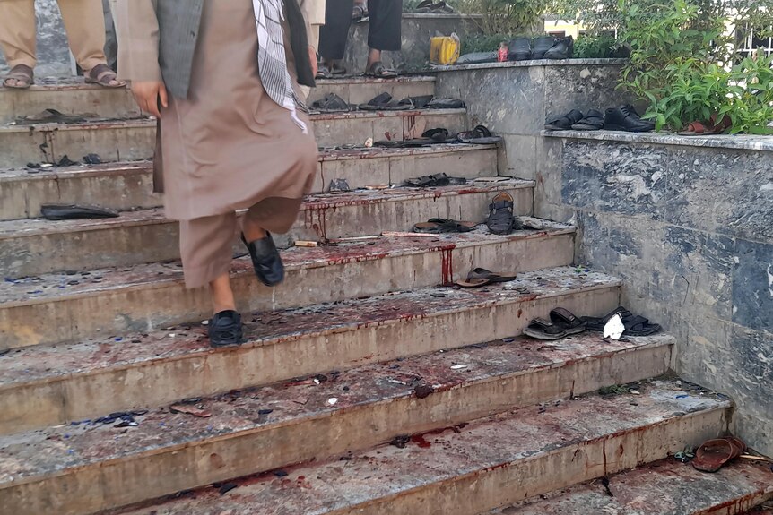 A man walks down blood-stained steps of a mosque.
