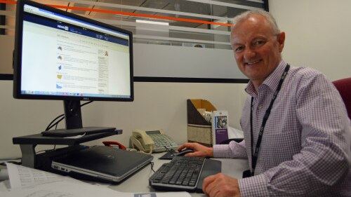 Antony Green smiles at the camera in front of a computer in an office.