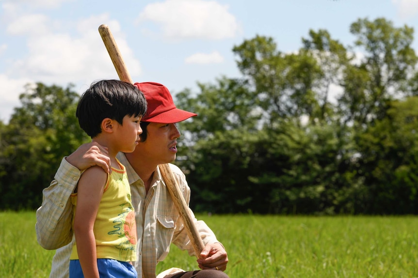 A still from the film Minari with Alan S. Kim and Steven Yeun, a father and his young son looking out onto a field