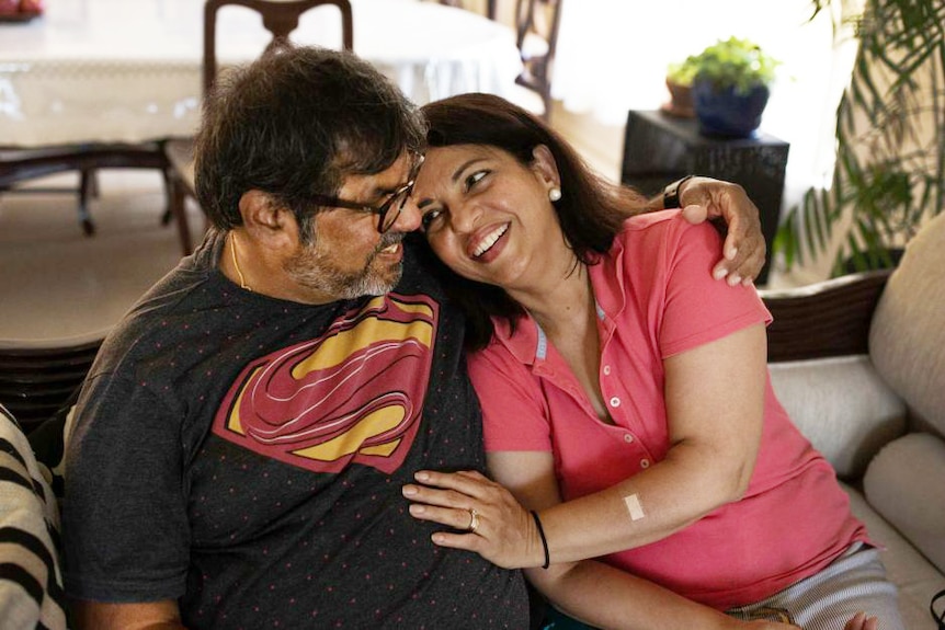 couple on couch in, woman smiling at man as she leans into his arms