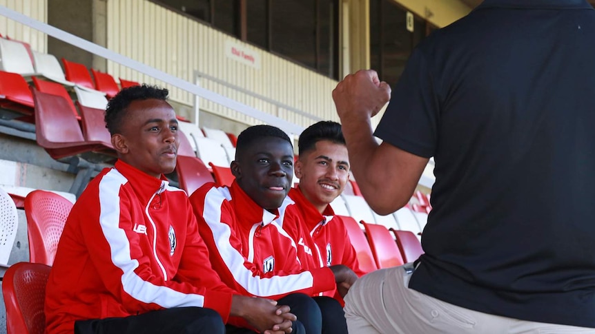 Man talks to three junior soccer players.