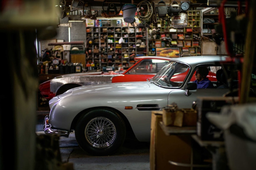 A man sitting in his Aston Martin DB5.