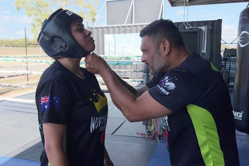 A man clips together the chin strap of Sahara's headguard