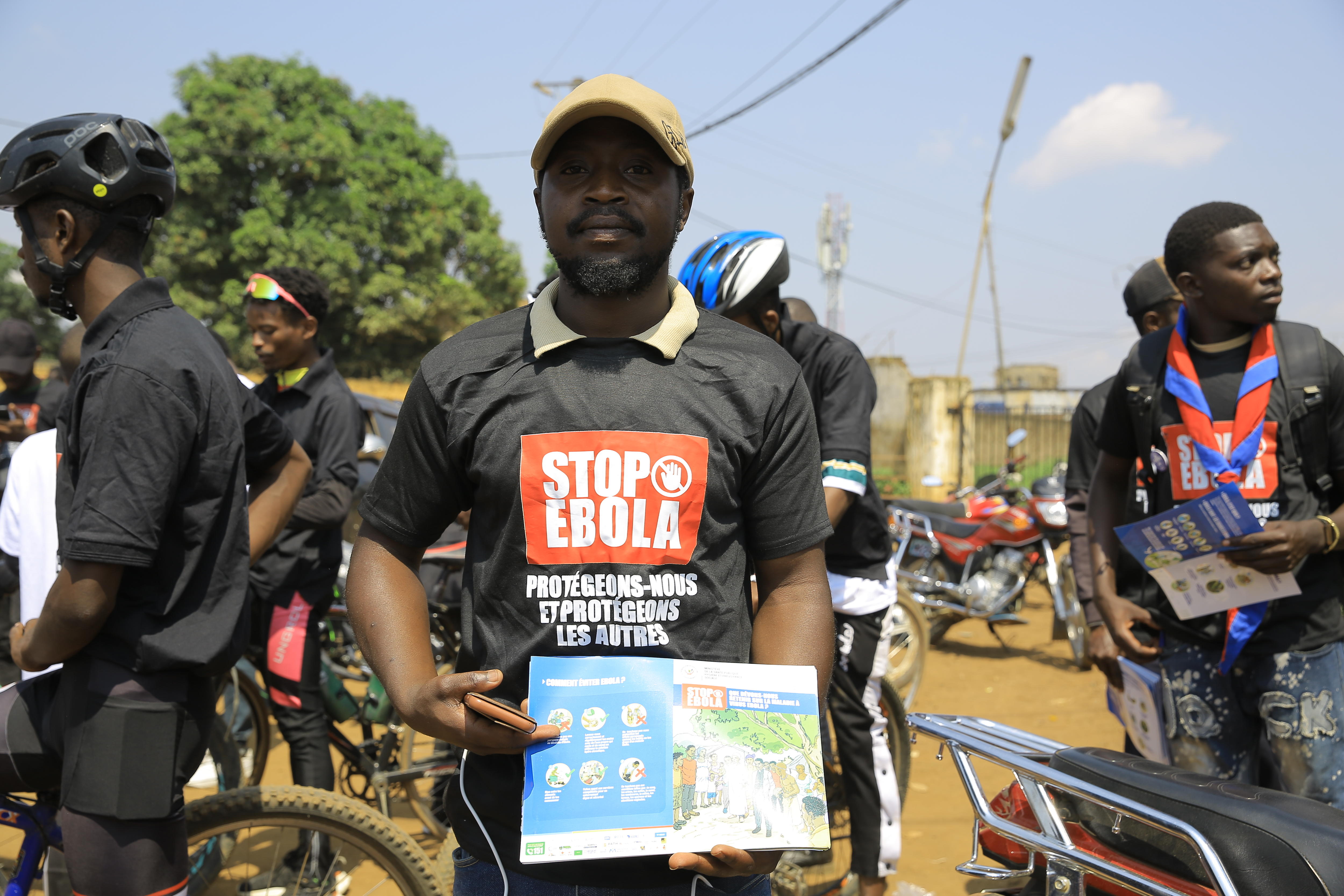 People wearing shirts that say 'stop ebola' holding information pamphlets