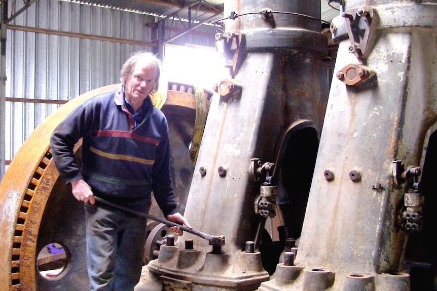 A man standing in front of a large piece of machinery.