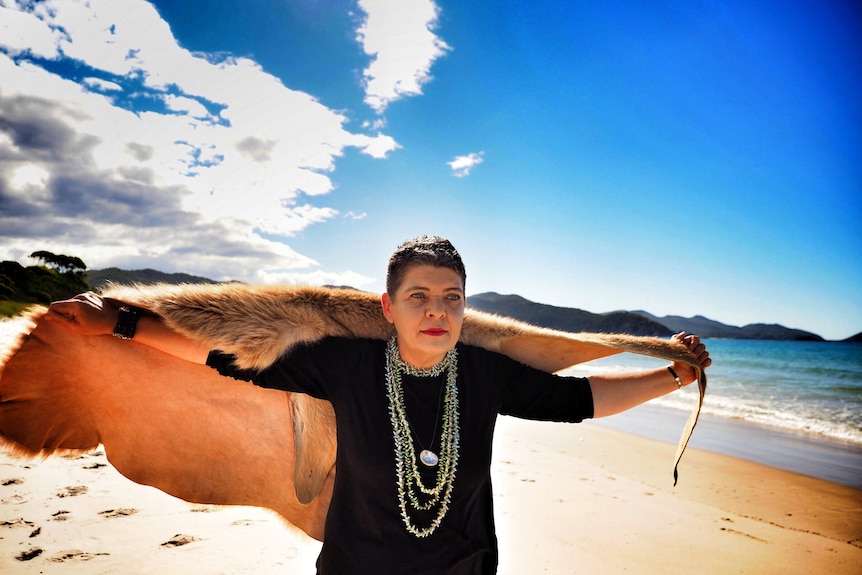 A portrait of Tasmanian Aboriginal woman with wallaby skin cloak flying like a cape behind her