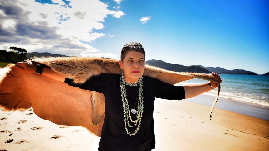 A portrait of Tasmanian Aboriginal woman with wallaby skin cloak flying like a cape behind her