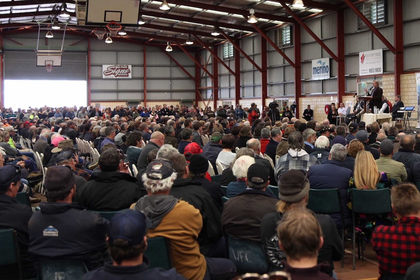 A large crowd of people, mostly seated, at a sports hall.