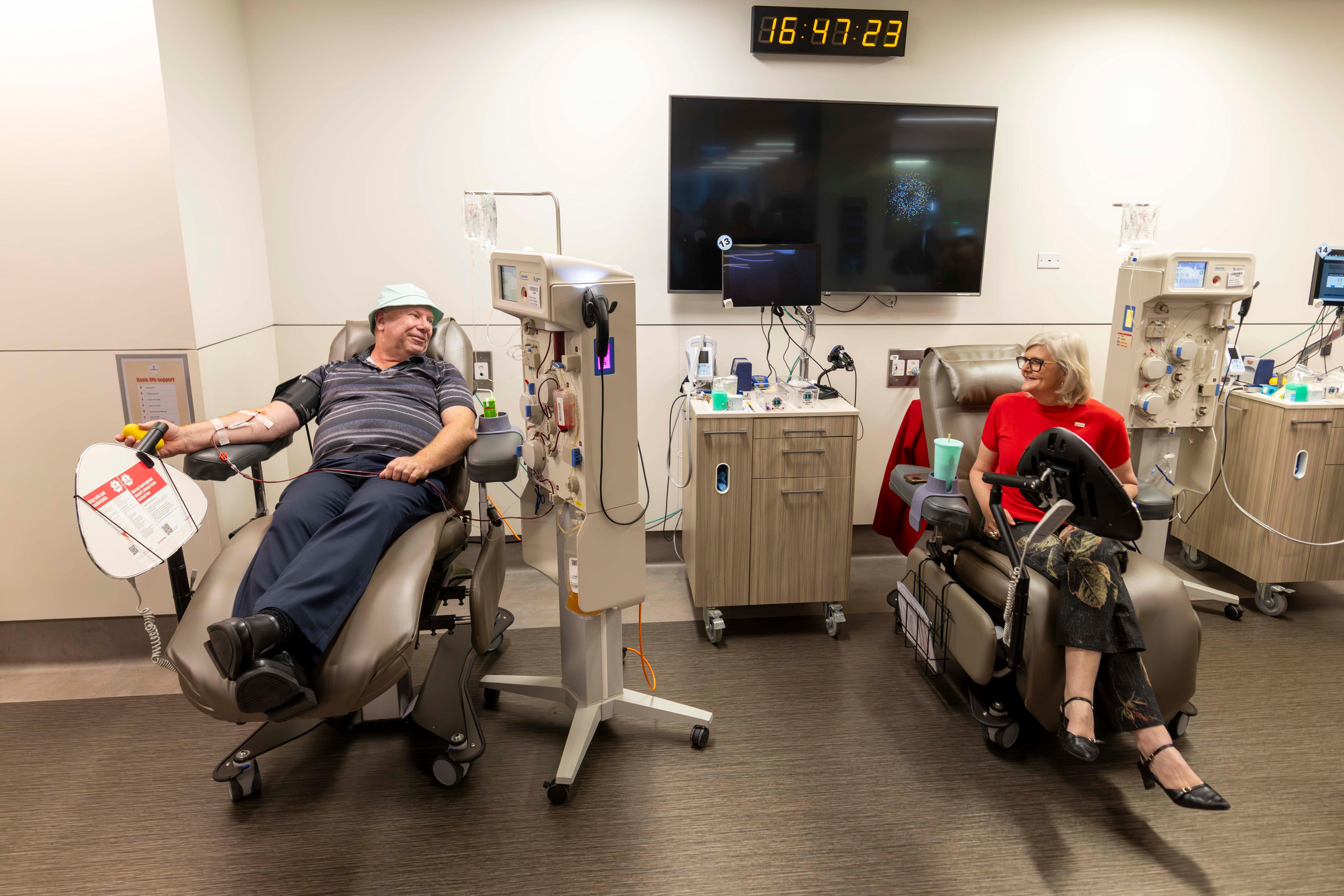 Trevor, a middle age man, sits donating blood next to Australia's governor-general Sam Mostyn, also donating blood.