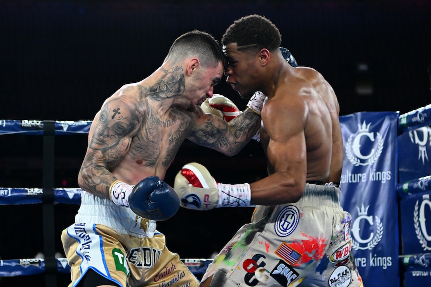 Two boxers clinch in a title fight.