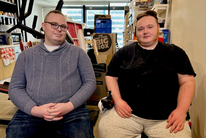 A photo of Lee (left) and Erin (right) sitting down. Lee wearing a grey top, Erin a black shirt. 
