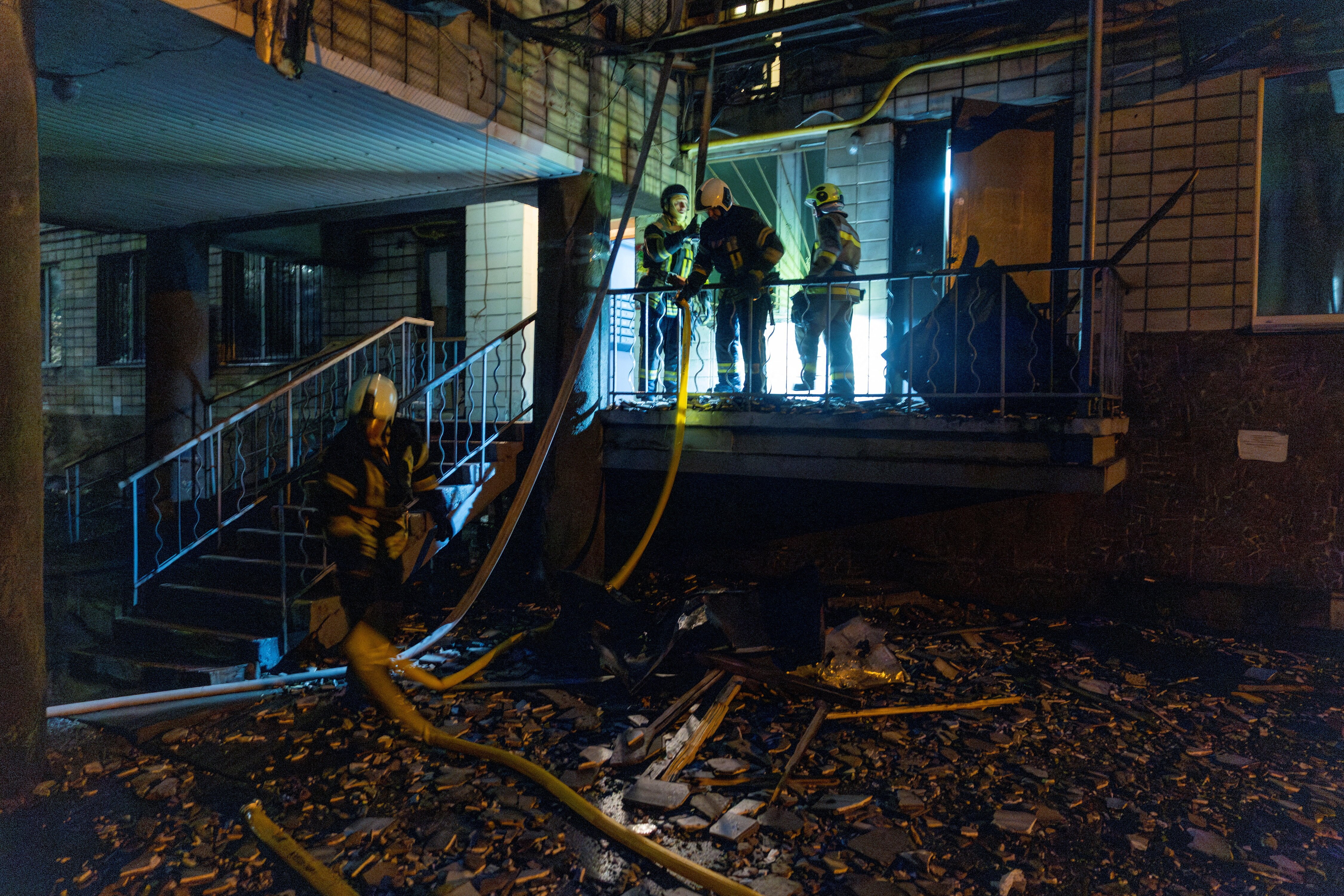 Firefighters working in a partially bombed out apartment building in darkness.