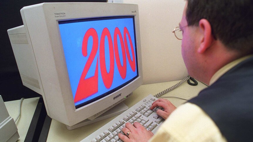 A man looks at a computer with the numeral 2000 on the screen