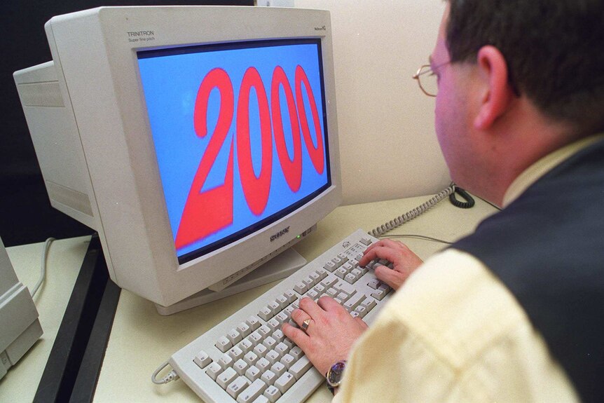 A man looks at a computer with the numeral 2000 on the screen