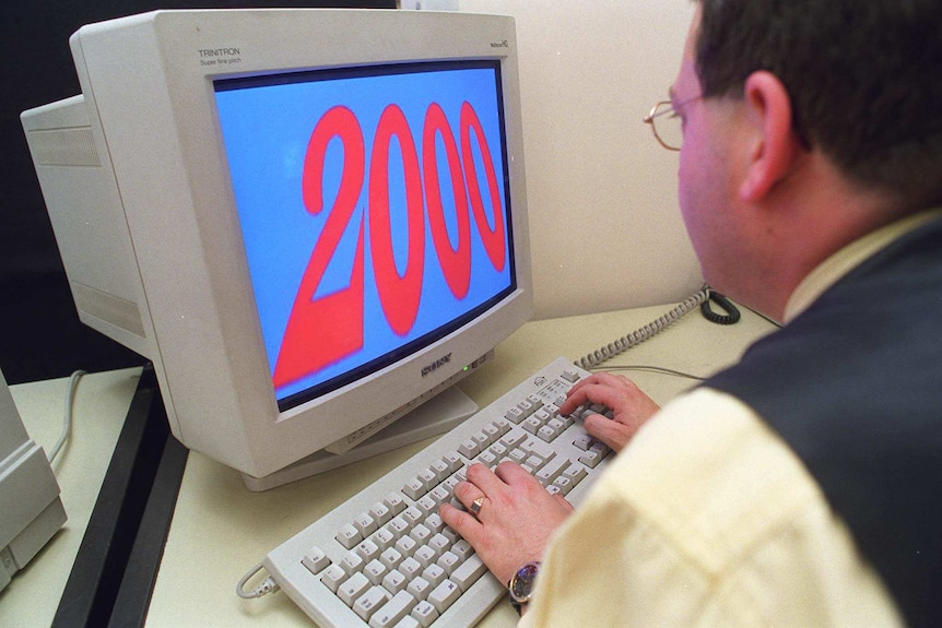 A man looks at a computer with the numeral 2000 on the screen