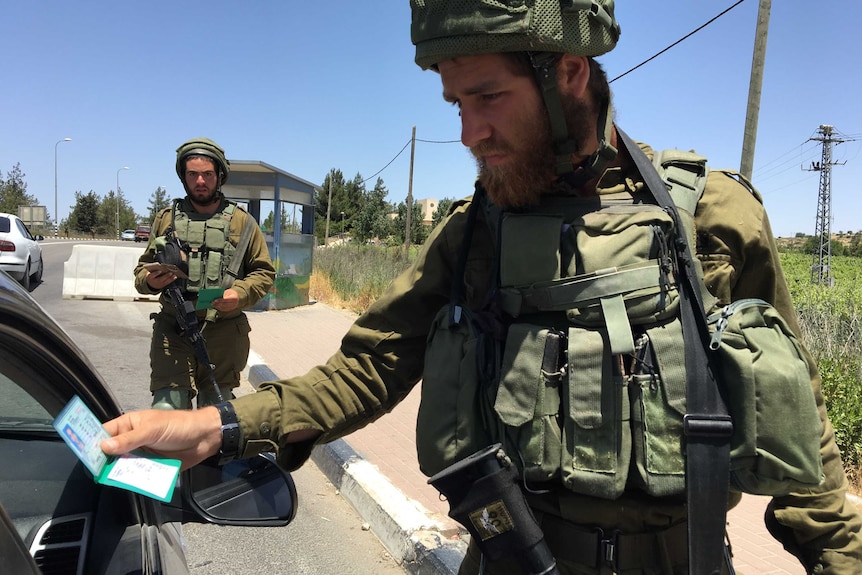 Soldiers stop a Palestinian's car at a checkpoint near Gush Etzion.
