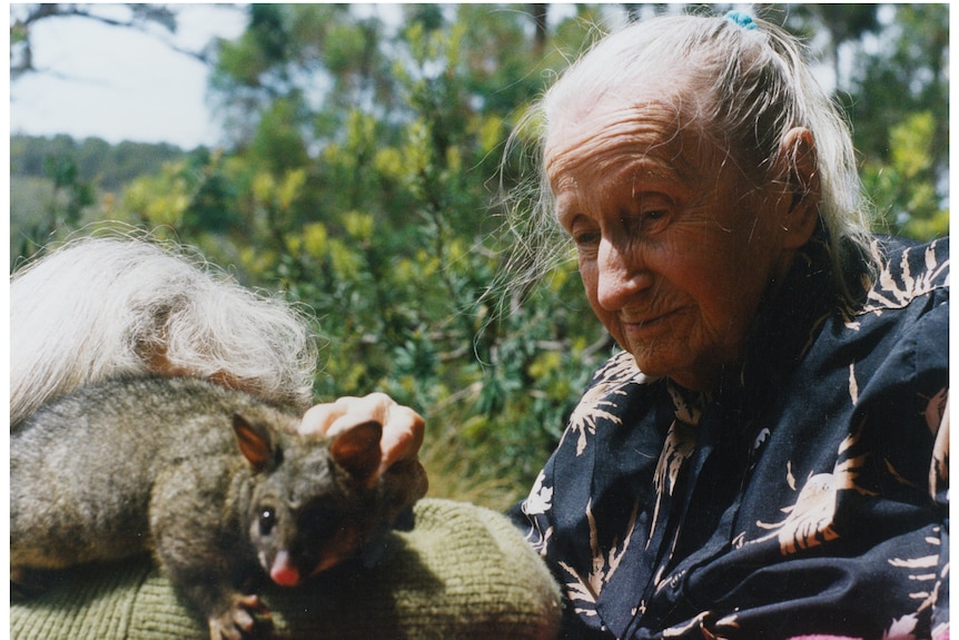 Edith Emery in her older age outside patting a possum.