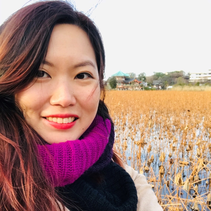 A woman poses for a photo in front of rice paddies